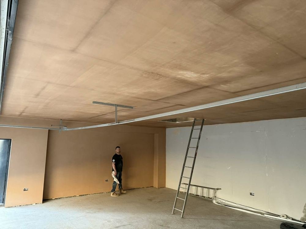 A large open room with the full ceiling and walls skimmed, a ladder standing against one wall