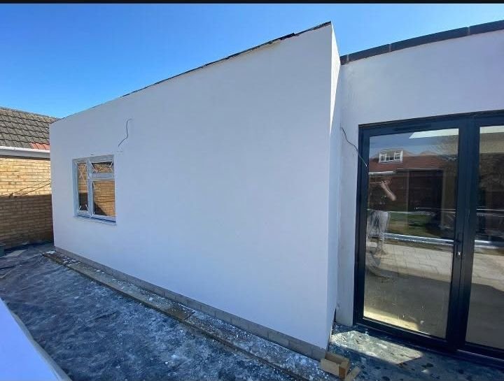 A single-storey extension rendered white on the outside, with bi-fold doors fitted
