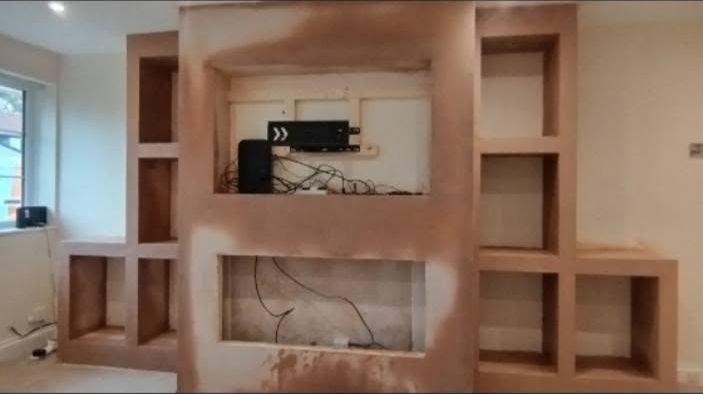 A built-in media wall with alcoves, plastered, with cabling left ready behind it